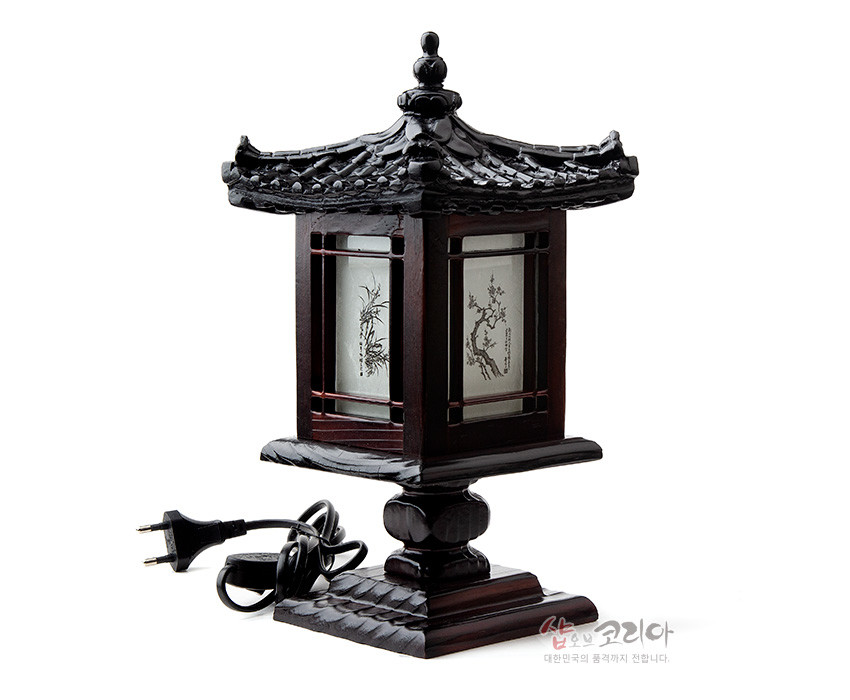 [텍스트: 샵오브코리아 대한민국의 품격까지 전합니다.] 짙은 목재로 조각된 사각 기와 지붕과 받침, 반투명 한지 패널에 매화·대나무 흑백 문양이 새겨진 전통 전기 좌등 장식