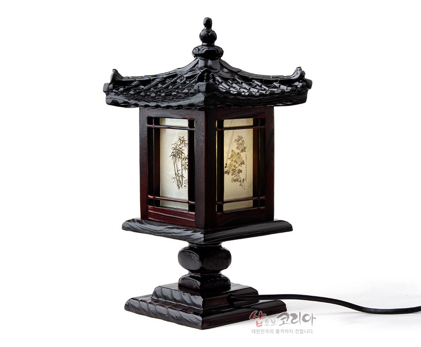 [텍스트: 샵오브코리아 대한민국의 품격까지 전합니다.] 짙은 갈색 목재와 흑색 기와 지붕 조각, 반투명 한지 패널에 대나무·매화 문양이 새겨진 전통 미니 좌등 장식