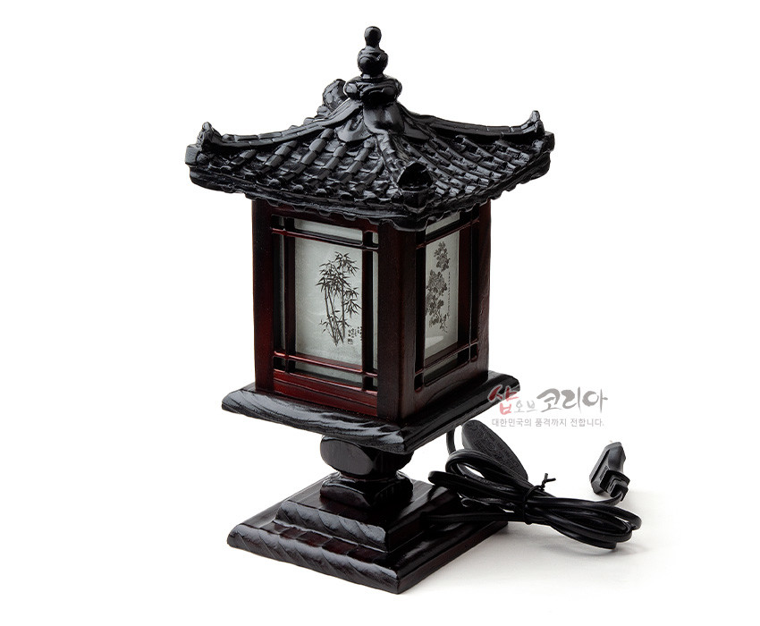 [텍스트: 샵오브코리아 대한민국의 품격까지 전합니다.] 짙은 흑갈색 목재와 기와지붕 조각, 반투명 한지 패널에 대나무 등 식물 문양이 인쇄된 전통 미니 좌등 형태의 조명등