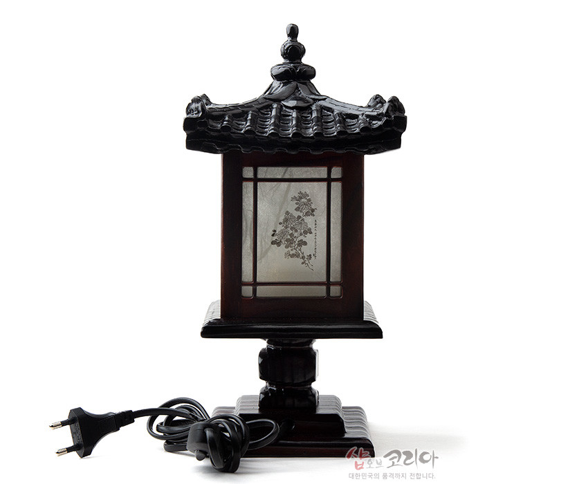 [텍스트: 샵오브코리아 대한민국의 숨결까지 전합니다.] 짙은 갈색 목재와 곡선 기와 지붕, 반투명 한지 패널에 수묵 매화 문양이 새겨진 전통 미니 좌등 형태 이미지