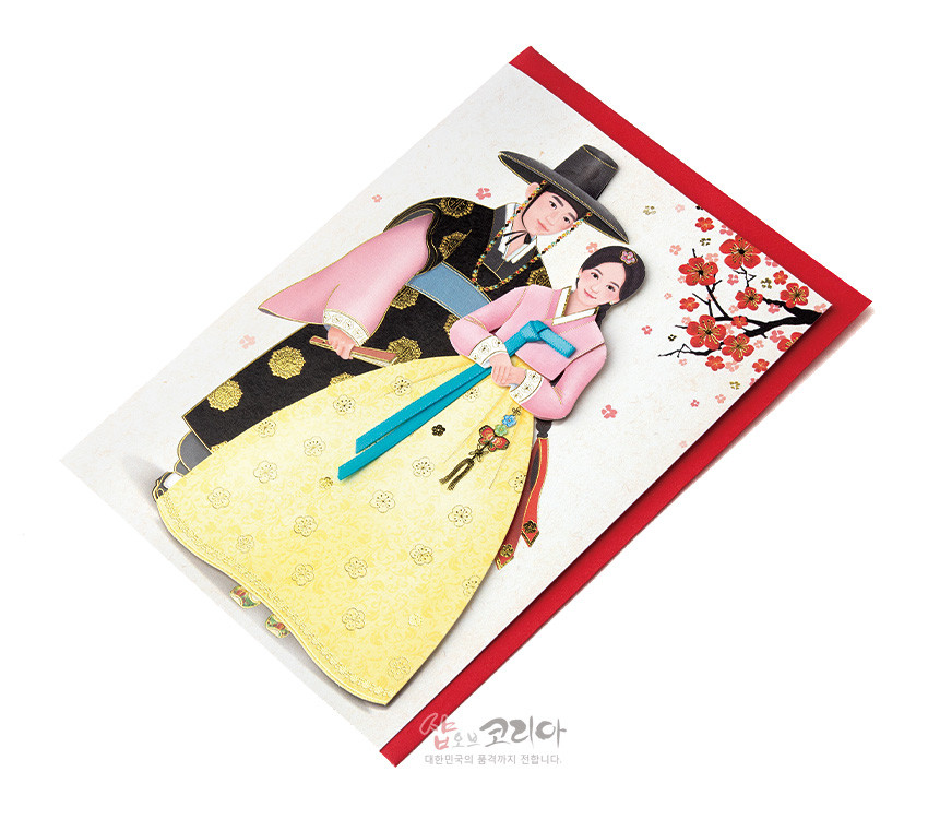 [텍스트: 샵오브코리아 대한민국의 품격까지 전합니다.] 전통 한복 입은 선비와 여인을 양각 기법으로 표현한 카드, 노란색 치마의 금색 꽃문양과 분홍·청색 대비, 매화 가지와 붉은 봉투 색상의 조화 이미지说明