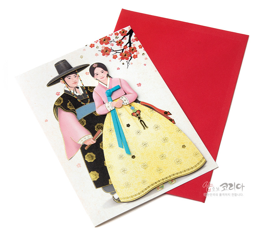 [텍스트: 샵오브코리아 대한민국의 품격까지 전합니다.] 전통 한복 입은 선비와 여인 일러스트 카드, 황금색 꽃문양 치마와 분홍색 저고리, 파란 색동 고름과 매듭 장식, 붉은 매화 가지가 배경인 디자인