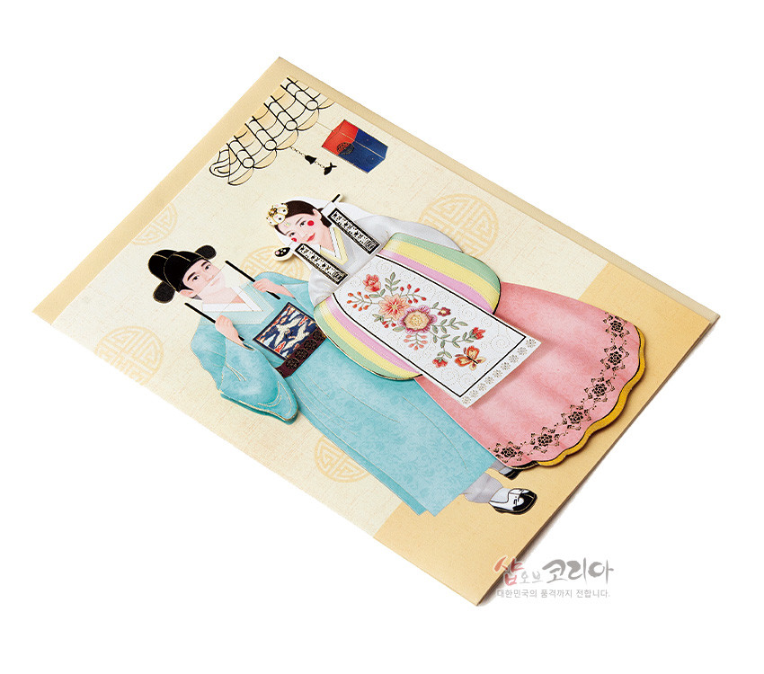 [텍스트: 샵오브코리아 대한민국의 품격까지 전달합니다.] 전통 혼례 한복 입은 신랑신부 일러스트 카드, 파스텔 색감 비단 느낌과 수복 문양 배경, 자수풍 꽃문양과 색동 배자 장식 표현 이미지