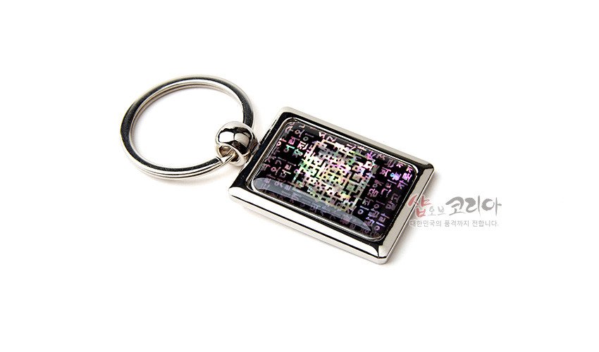 [텍스트: 샵오브코리아 대한민국의 품격까지 전합니다.] 사각 금속 테두리 안에 채색 자개를 상감하여 한글 시조문 문양을 넣고 오방색 계열의 오묘한 빛을 담은 열쇠고리 디자인