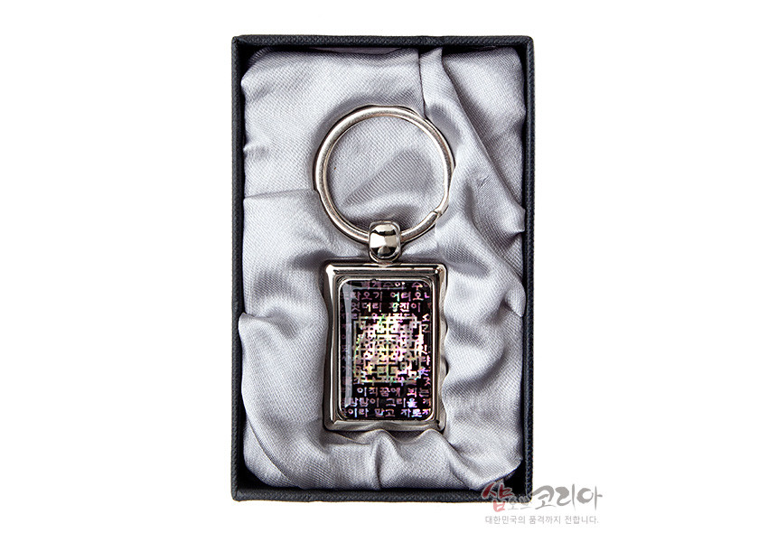 [텍스트: 샵코리아 대한민국의 혼과 정까지 전합니다.] 사각 금속 테두리 안 채색 자개 상감 장식, 어두운 바탕 위 오방색 계열 시조문 한글 문양이 빛에 따라 반사되는 열쇠고리 디자인