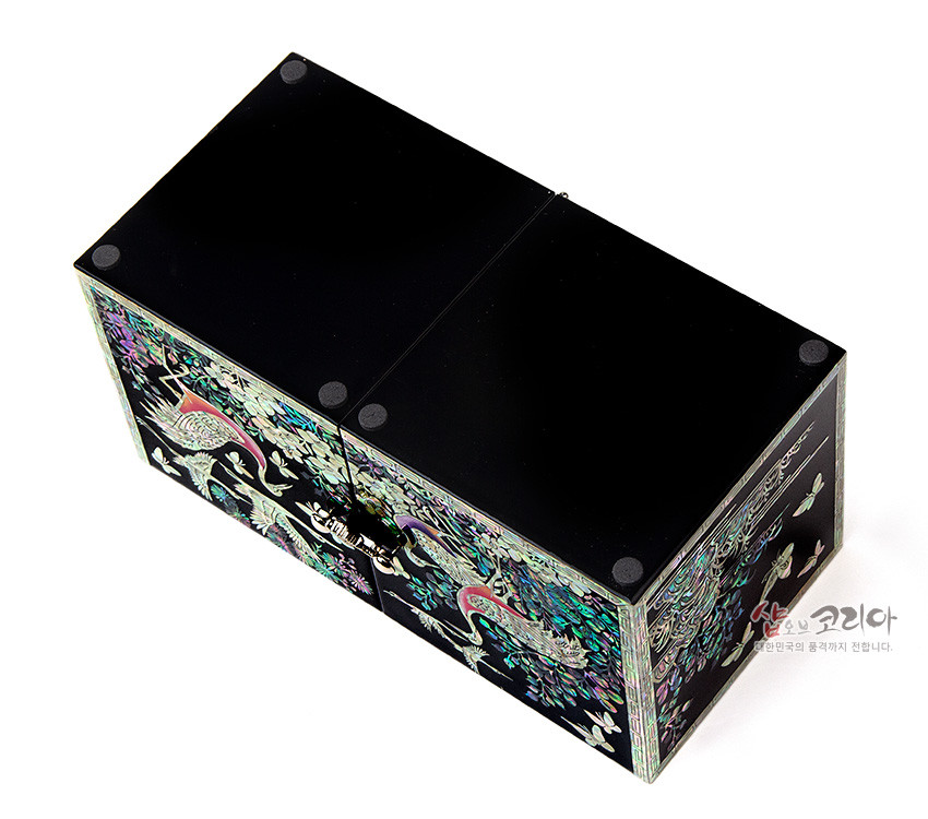 [텍스트: 샵오브코리아 대한민국의 품격까지 전합니다.] 흑색 옻칠 위 자개 상감 기법, 장생도 학과 소나무·구름 문양이 오색광으로 빛나는 쌍합 보석함 모습