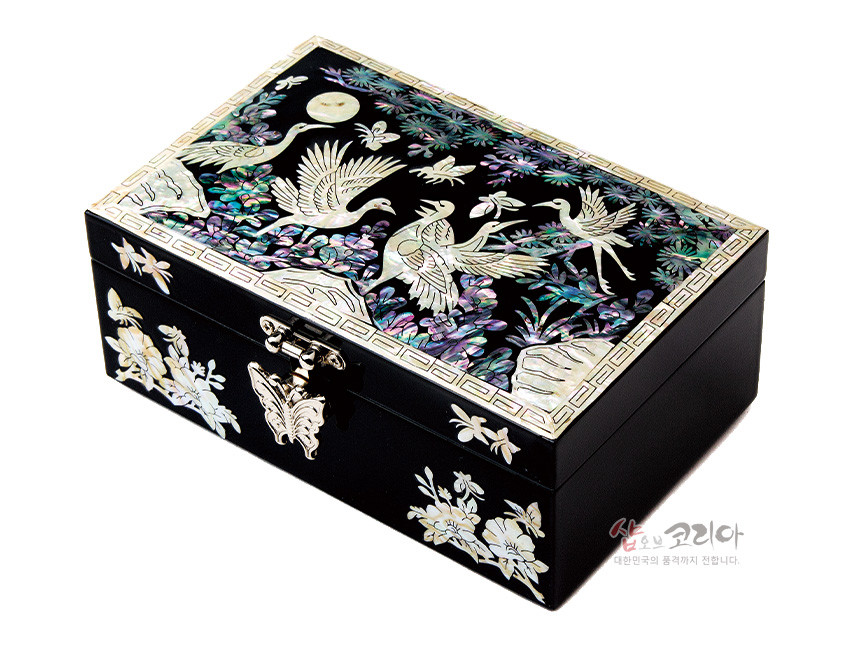 [텍스트: 샵오브코리아 대한민국의 품격까지 전합니다.] 흑색 옻칠 위 자개 상감으로 학과 달, 소나무와 꽃문양을 섬세하게 표현한 직사각 형태 나전칠기 보석함 디자인