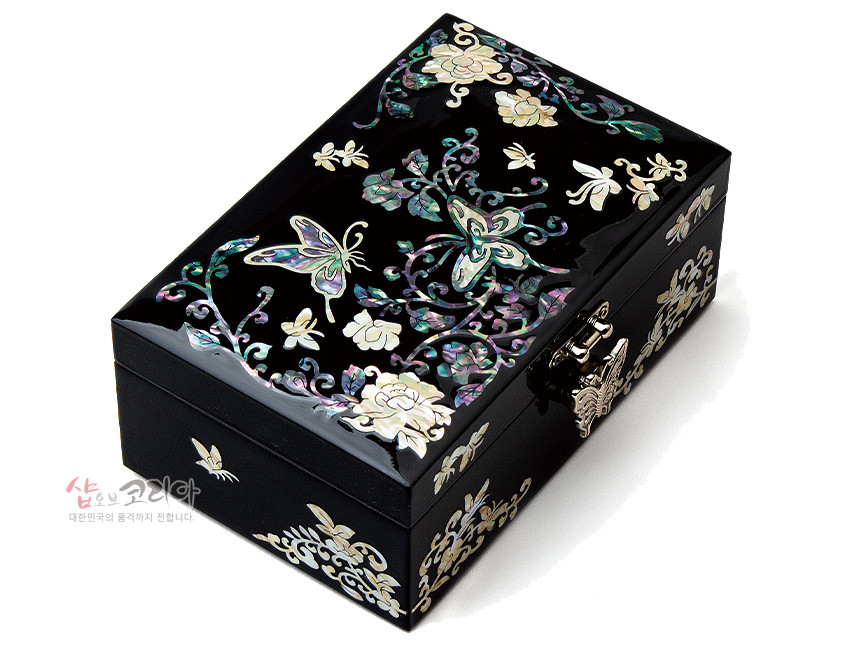 [텍스트: 샵오브코리아 대한민국의 품격까지 전합니다.] 흑색 옻칠 바탕 위 자개 상감 기법으로 나비와 모란 덩굴문을 화려하게 장식한 직사각형 보석함 디자인