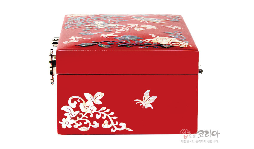[텍스트: 샵오브코리아 대한민국의 품격까지 전합니다.] 붉은 옻칠 바탕 위에 자개 상감으로 나비와 꽃넝쿨 문양을 장식한 직사각 금속 잠금 보석함 이미지 설명