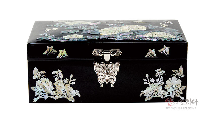 [텍스트: 샵오브코리아 대한민국의 품격까지 전합니다.] 흑색 옻칠 바탕 위에 자개 상감으로 모란꽃과 나비, 꽃문양을 섬세하게 장식한 금속 잠금장치 직사각 보석함 모습