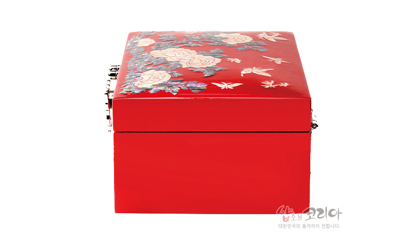 [텍스트: 샵오브코리아 대한민국의 품격까지 전달합니다] 붉은 옻칠 표면에 자개 상감으로 모란꽃과 나비 문양을 장식한 직사각형 나전칠기 보석함 측면 모습