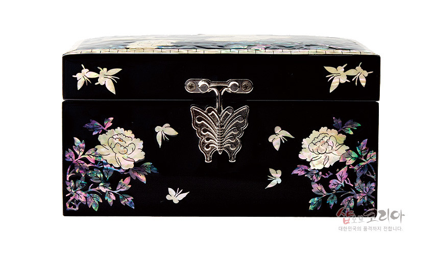 [텍스트: 샵오브코리아 대한민국의 품격까지 전합니다.] 흑색 옻칠 바탕에 자개 상감 기법으로 모란과 나비, 나뭇잎 문양을 수놓고 은빛 나비 모양 금속 잠금장식을 더한 직사각 보석함 정면 모습