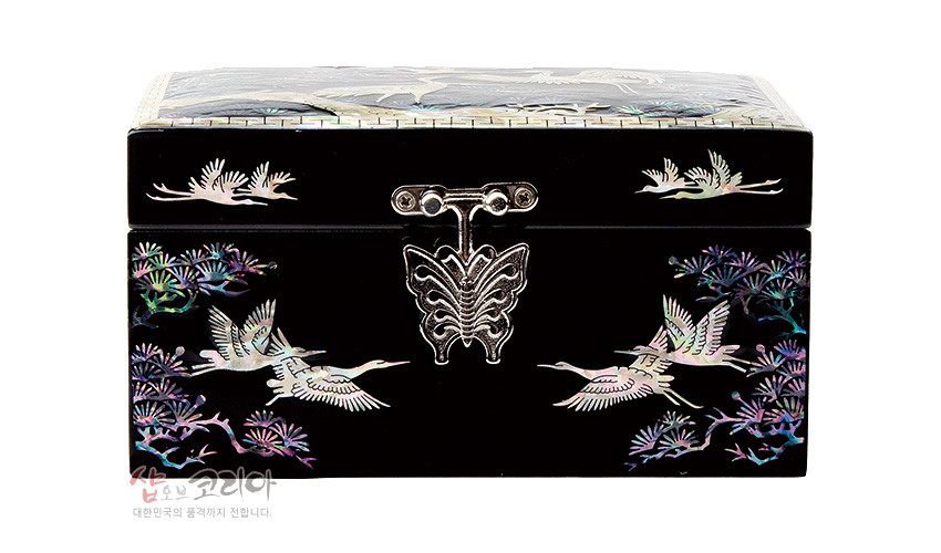 [텍스트: 샵오브코리아 대한민국의 품격까지 전합니다] 흑색 옻칠 바탕에 자개 상감으로 송학과 소나무, 만월 문양을 정교하게 표현하고 금속 나비 잠금장식을 더한 직사각 보석함 이미지 설명