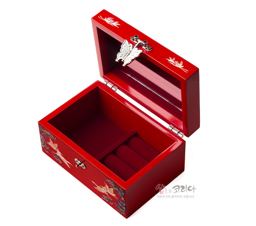 [텍스트: 샵오브코리아 대한민국의 품격까지 전합니다.] 적색 옻칠 바탕 위 자개 상감 송학과 소나무 문양, 금속 나비 장식 잠금장치와 내부 링 수납 구조 보석함 디자인