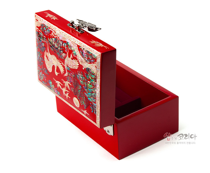 [텍스트: 샵오브코리아 대한민국의 품격까지 전합니다.] 적색 옻칠 바탕 위 자개 상감으로 송학과 소나무, 만월과 산수 문양을 정교하게 표현한 금속 잠금장치 직사각 보석함 이미지