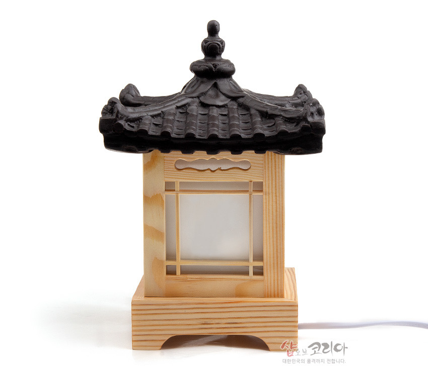 [텍스트: 샵오브코리아 대한민국의 품격까지 전합니다.] 검은 기와지붕과 연한 목재 사각 기단, 창호지와 창살 구조가 조화를 이룬 전통 한옥 형태 미니 좌등 형상
