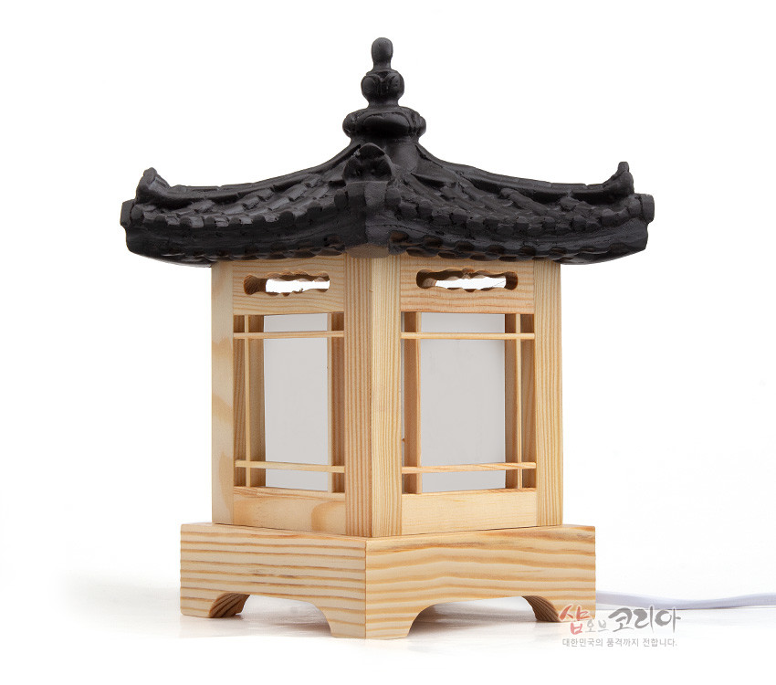 [텍스트: 샵오브코리아 대한민국의 즐거까지 전달합니다.] 천연 목재 사각 기단과 창살 구조, 반투명 백색 창호지, 검은색 기와 지붕 장식이 어우러진 전통 한옥형 미니 좌등 디자인