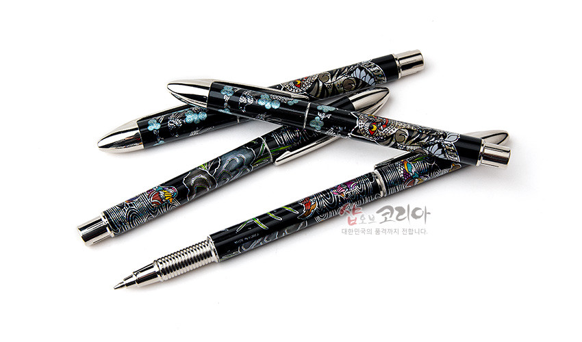 [텍스트: 샵오브코리아 대한민국의 품격까지 전합니다.] 흑색 옻칠 바탕 위 자개 상감 기법으로 호작도·원앙·매화 문양을 새긴 은색 금속 장식 볼펜 4종 세트 모습