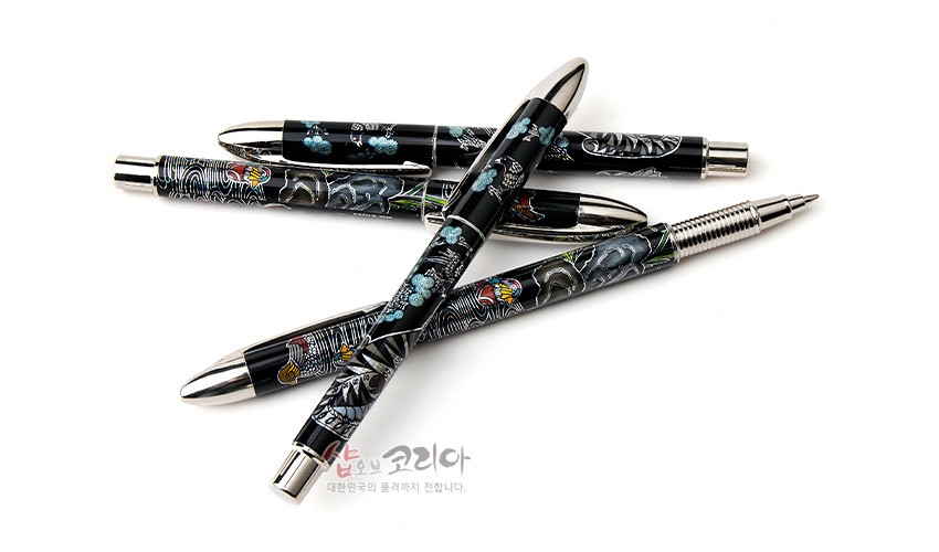 [텍스트: 샵오브코리아 대한민국의 품격까지 전합니다.] 흑색 옻칠 바탕 위 자개 상감으로 호랑이·까치·원앙과 매화·구름 문양을 넣은 금속 장식 볼펜 4종 세트 이미지 설명