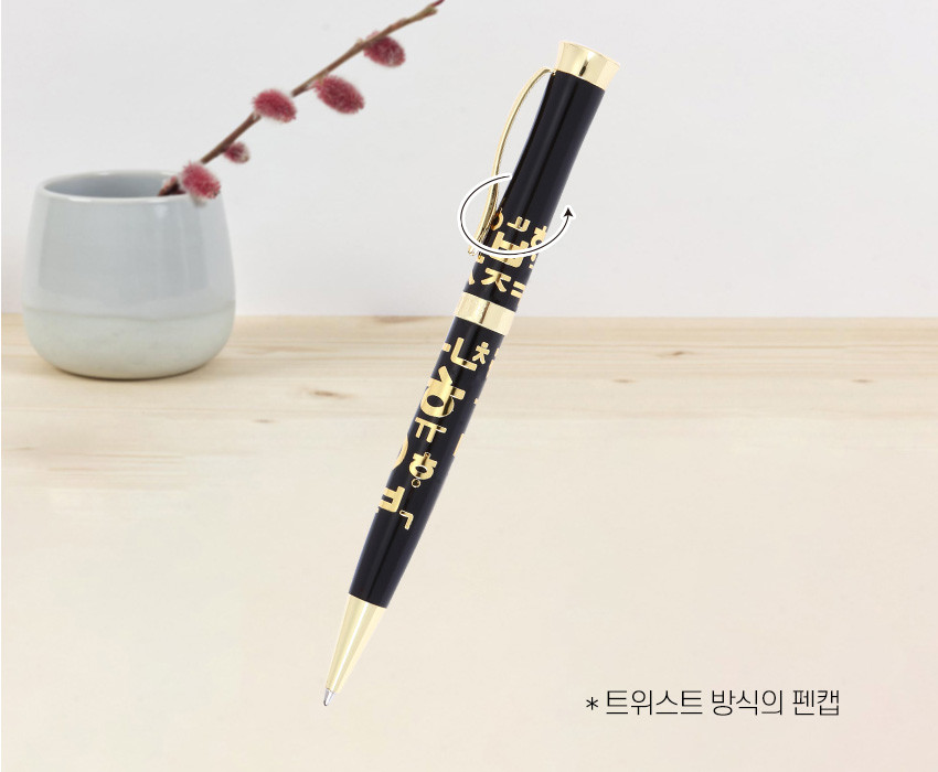 [텍스트: * 트위스트 방식의 펜캡] 검은색 바디 위 금색 한글 자음 문양과 금속 클립, 펜촉이 조화를 이루는 볼펜 디자인