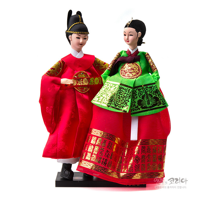 [텍스트: 샵오브코리아 대한민국의 품격까지 전합니다.] 붉은 비단 곤룡포와 녹·홍색 비단 원삼에 금박 궁중 문양과 한자 문양을 정교하게 더한 전통 왕과 왕비 한복인형 장식