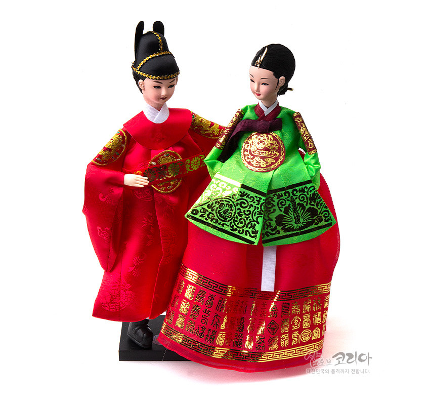 [텍스트: 샵오브코리아 대한민국의 품격까지 전달합니다.] 붉은 비단 곤룡포와 녹색·홍색 비단 활옷에 금박 궁중문양과 한자 문양을 더한 전통 혼례 왕과 왕비 한복인형 구성