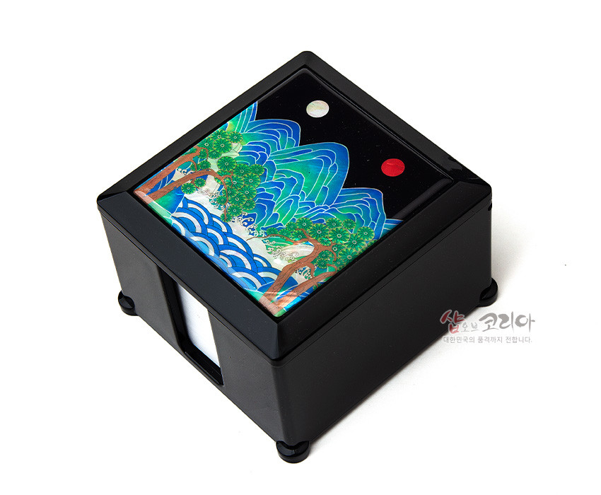 [텍스트: 샵오브코리아 대한민국의 품격까지 전합니다.] 검은 옻칠 메모지함 상단에 자개 상감 기법으로 표현된 일월오봉도 산수와 청록·청색 파도, 붉은 해와 흰 달 문양이 조화된 디자인