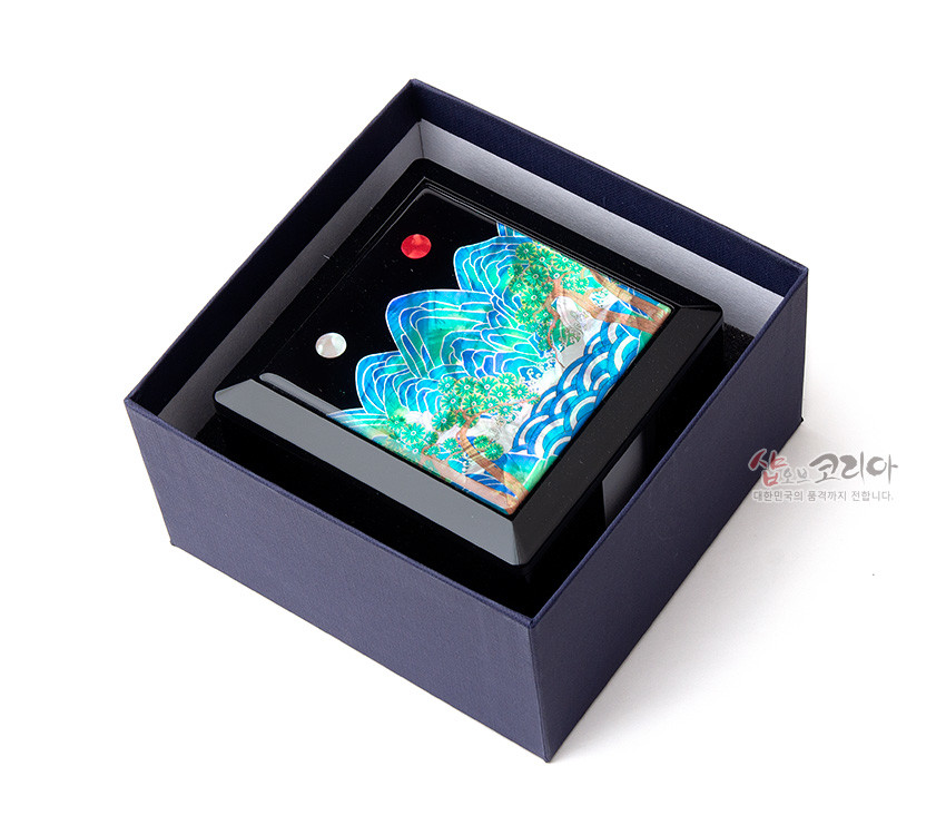 [텍스트: 샵오브코리아 대한민국의 품격까지 전합니다.] 검은 옻칠 메모지함 상단에 자개 상감으로 표현된 청록색 산과 푸른 파도, 붉은 해와 흰 달이 어우러진 일월오봉도 문양 장식 이미지