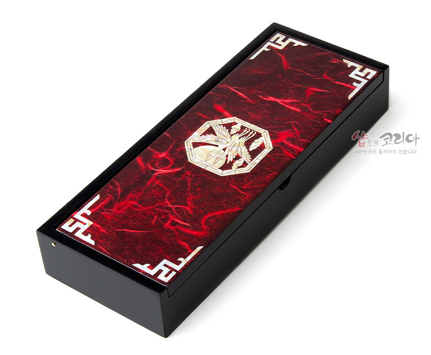 [텍스트: 샵오브코리아 대한민국의 품격까지 전합니다.] 붉은 한지 바탕 위 자개 상감 적학 문양과 흰색 전통 기하학 모서리 장식을 더한 흑색 목재 필함 디자인