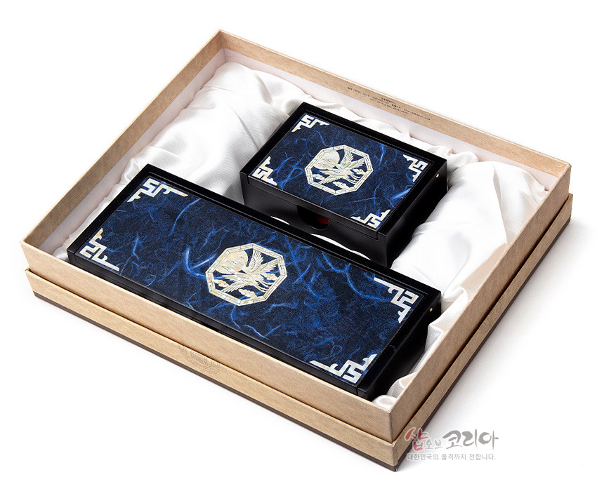 [텍스트: 샵오브코리아 대한민국의 품격까지 전합니다.] 짙은 청색 한지 바탕 위 자개 상감 청학 문양과 흰색 전통 기하학 테두리가 조화를 이룬 필함·명함함 세트 이미지