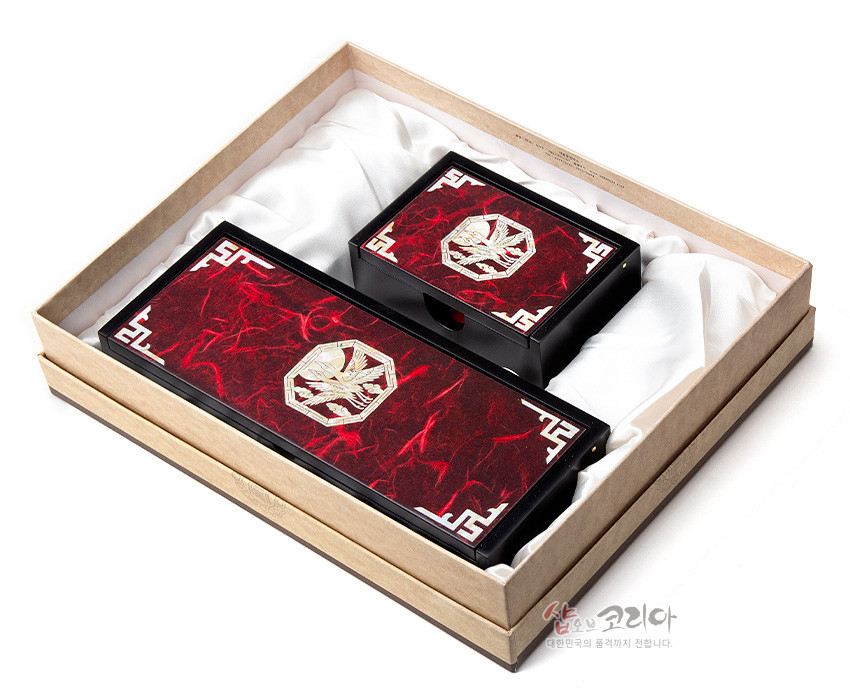 [텍스트: 샵오브코리아 대한민국의 품격까지 전합니다.] 붉은 마블 한지 바탕 위 자개 적학 문양과 흰색 기하학 모서리 장식이 놓인 흑색 목재 필함·명함함 세트 이미지