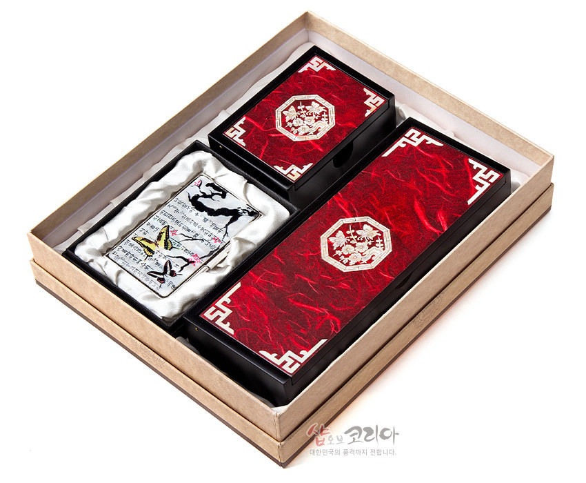 [텍스트: 샵오브코리아 대한민국의 품격까지 전합니다.] 붉은 한지 질감 바탕에 백색 매화와 전통 기하 문양, 자개 장식을 더한 필함·명함함·명함케이스 세트 이미지