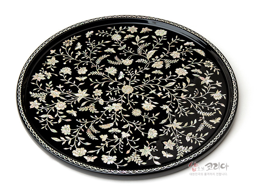 [텍스트: 샵오브코리아 대한민국의 품격까지 전합니다.] 검은 옻칠 바탕 위 자개 상감으로 섬세한 넝쿨과 꽃문양을 가득 채운 원형 나전칠기 쟁반 디자인