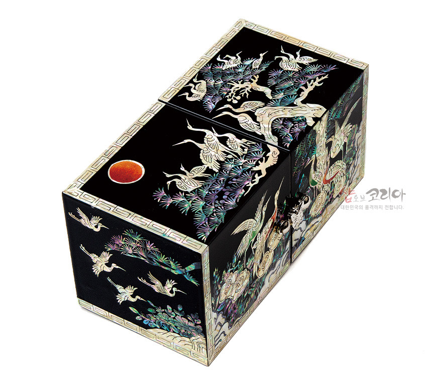 [텍스트: 샵오브코리아 대한민국의 품격까지 전합니다.] 흑색 옻칠 바탕 위 자개 상감으로 송학도와 소나무, 구름, 해를 섬세하게 표현한 직사각형 쌍합 형태의 나전칠기 보석함 이미지 설명