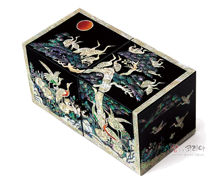 [텍스트: 샵오브코리아 대한민국의 품격까지 전합니다.] 흑색 옻칠 위 자개 상감 기법으로 소나무와 학, 구름, 붉은 해를 정교하게 표현한 사각 쌍합 디자인