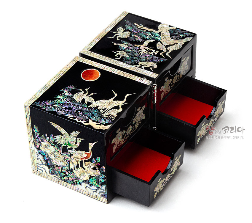 [텍스트: 샵오브코리아 대한민국의 혼과 정까지 전합니다.] 흑색 옻칠 바탕에 자개 상감으로 송학도, 소나무와 구름, 일월 문양을 표현한 사각 쌍합, 붉은 내부 안감 대비가 돋보이는 구성