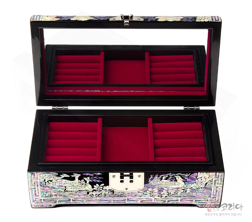 [텍스트: 샵오브코리아 대한민국의 품격까지 전합니다] 흑색 옻칠 위 자개 상감으로 소나무와 학 문양을 넣고 내부는 붉은 벨벳 칸막이로 구성된 장방형 보석함 이미지 설명