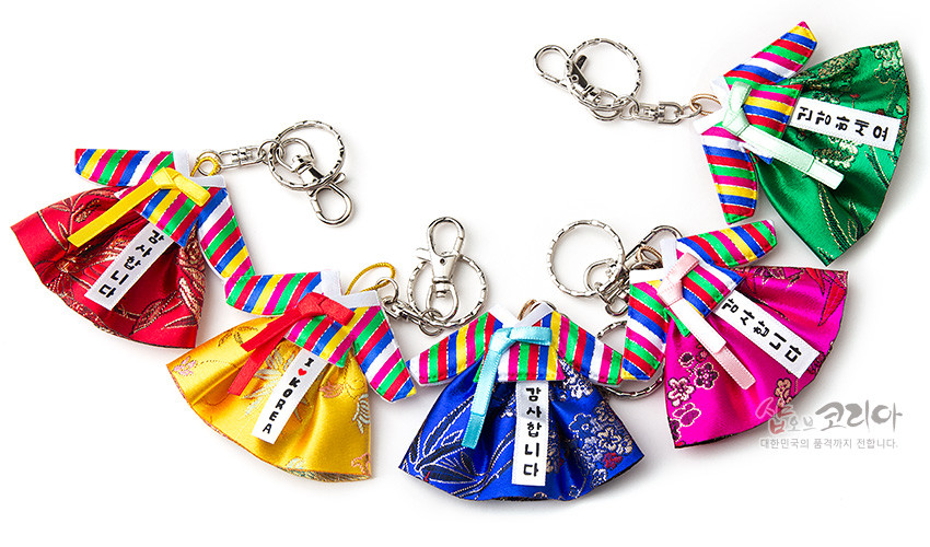 [텍스트: 감사합니다, 고마워요, 귀요미야, 사랑합니다] 색동 고름과 비단 치마로 구성된 한복 모양 금속 열쇠고리, 오방색 줄무늬와 전통 꽃문양 장식