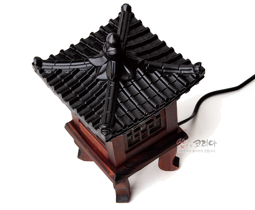 [텍스트: 샵오브코리아 대한민국의 품격까지 전합니다.] 짙은 갈색 목재와 흑색 기와지붕이 조화를 이루는 전통 정자 형 좌등, 완자문 창살과 네 모서리 곡선 다리 장식이 돋보이는 조명 소품