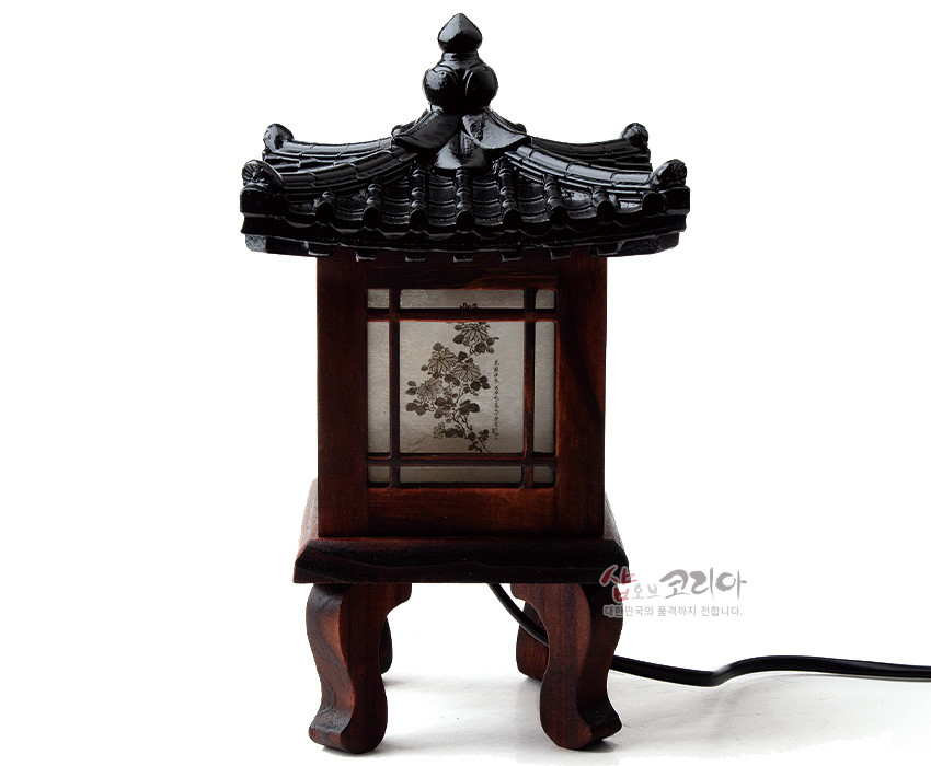 [텍스트: 샵오브코리아 대한민국의 품격까지 전합니다.] 흑색 기와 지붕과 짙은 목재 구조, 반투명 창호지에 흑백 사군자 문양이 인쇄된 전통 정자 형태 좌등 이미지 설명