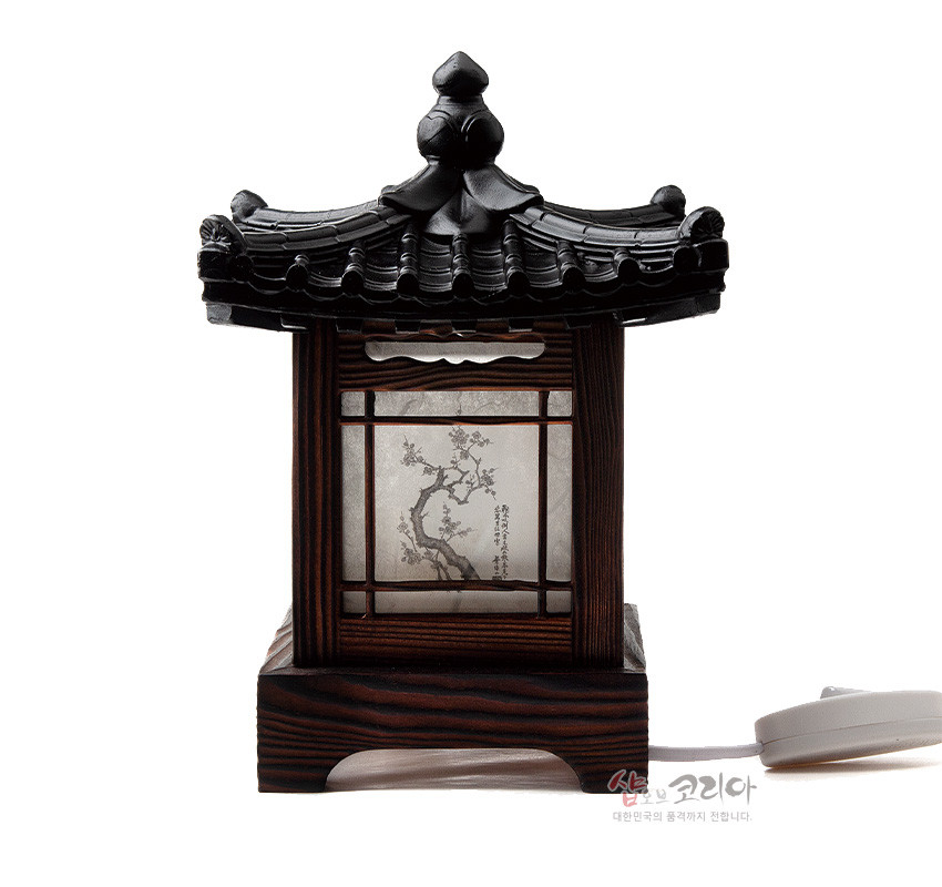 [텍스트: 샵오브코리아 대한민국의 품격까지 전합니다.] 흑색 기와 지붕과 짙은 목재 구조, 한지창에 먹선으로 표현된 매화 사군자 수묵화와 창살 무늬가 어우러진 전통 좌등 디자인