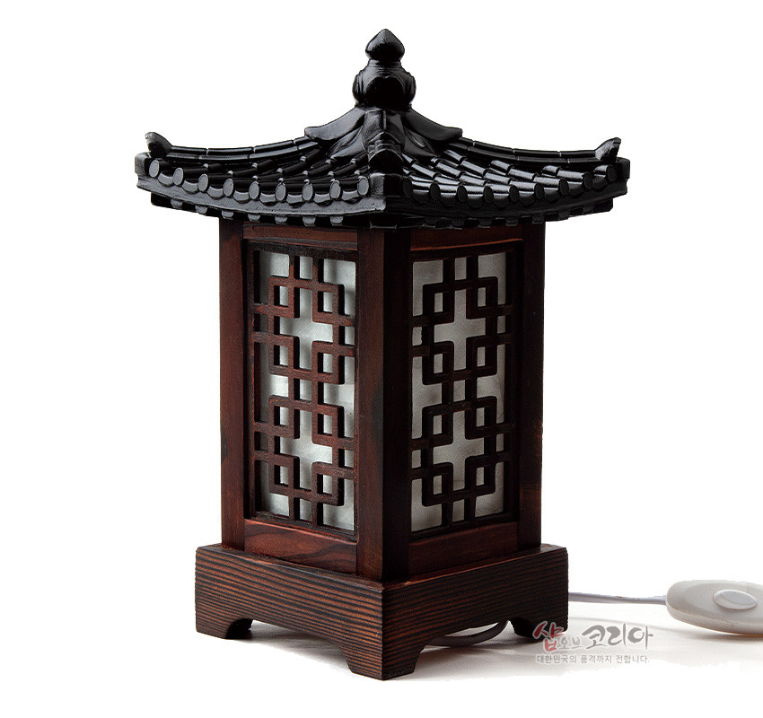 [텍스트: 샵오브코리아 대한민국의 품격까지 전합니다.] 짙은 갈색 목재와 기와형 지붕, 한지 위 완자문 격자 창살이 조화를 이룬 사각 전통 미니 좌등 디자인