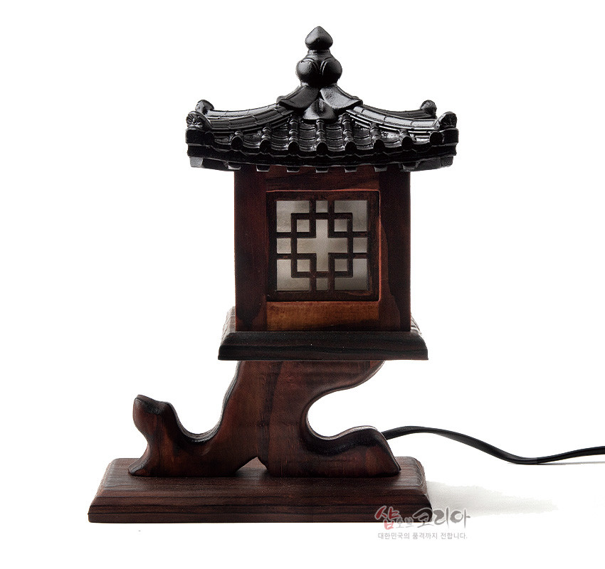 [텍스트: 샵오브코리아 대한민국의 품격까지 전합니다.] 짙은 갈색 원목과 흑색 기와 지붕, 반투명 창호에 완자 격자문을 더한 전통 누각 형식 전기 좌등 이미지