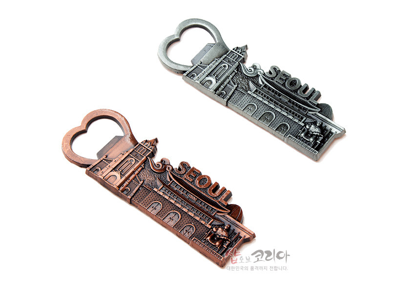 [텍스트: SEOUL] 금속 재질의 병따개 겸용 자석, 서울 성곽과 문루·성문을 양각으로 표현하고 앤틱 실버·브론즈 색상으로 마감한 입체 부조 장식