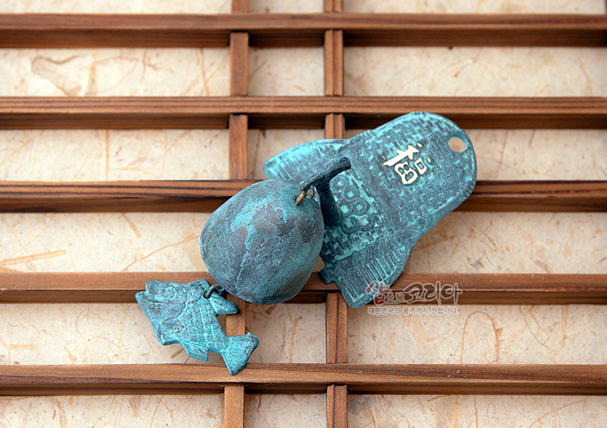 [텍스트: 福, 샵오브코리아 대한민국 전통까지 전합니다] 청동 재질의 산화 청록색 마감 문종과 물고기 장식, 기와와 복자 문양이 새겨진 전통 풍경 소품