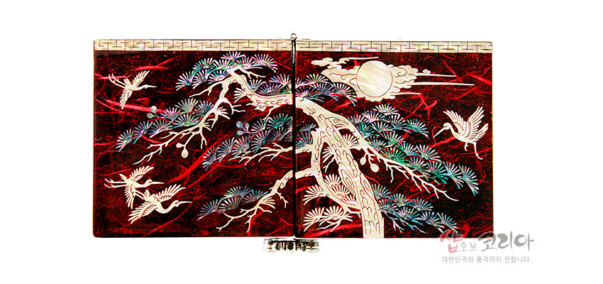 [텍스트: 샵오브코리아 대한민국의 품격까지 전합니다.] 붉은 옻칠 바탕 위 자개 상감 기법으로 소나무와 학, 구름과 해 문양을 정교하게 표현한 직사각형 쌍합 디자인