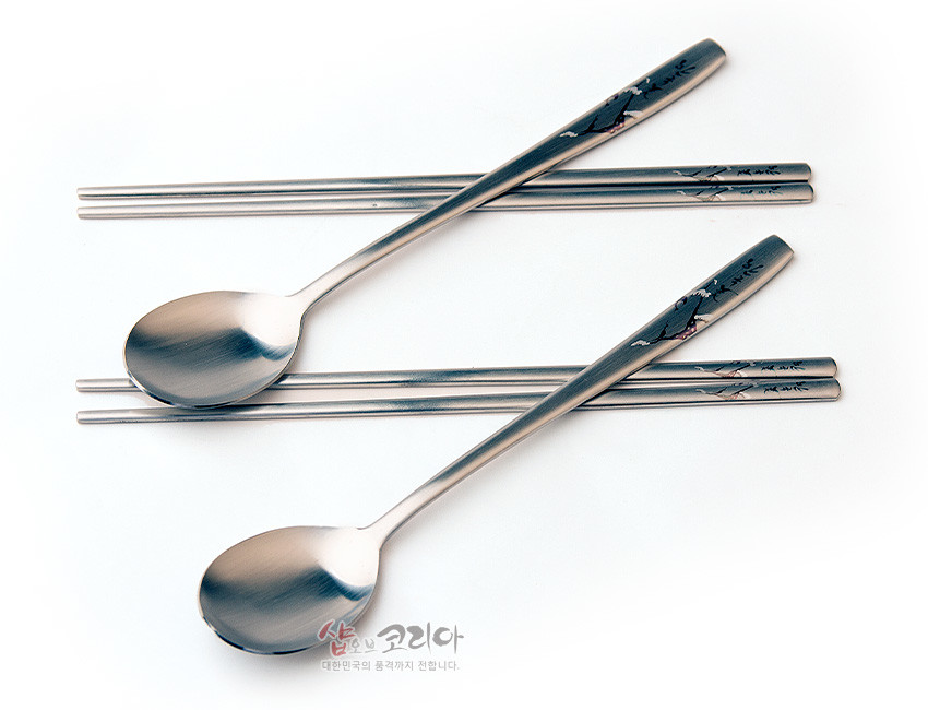 [텍스트: 샵오브코리아 대한민국의 품격까지 전합니다.] 무광 스테인리스 재질, 손잡이에 소나무 설경과 한글 서체가 은은한 색조로 인쇄된 2인용 수저·젓가락 세트 이미지 설명