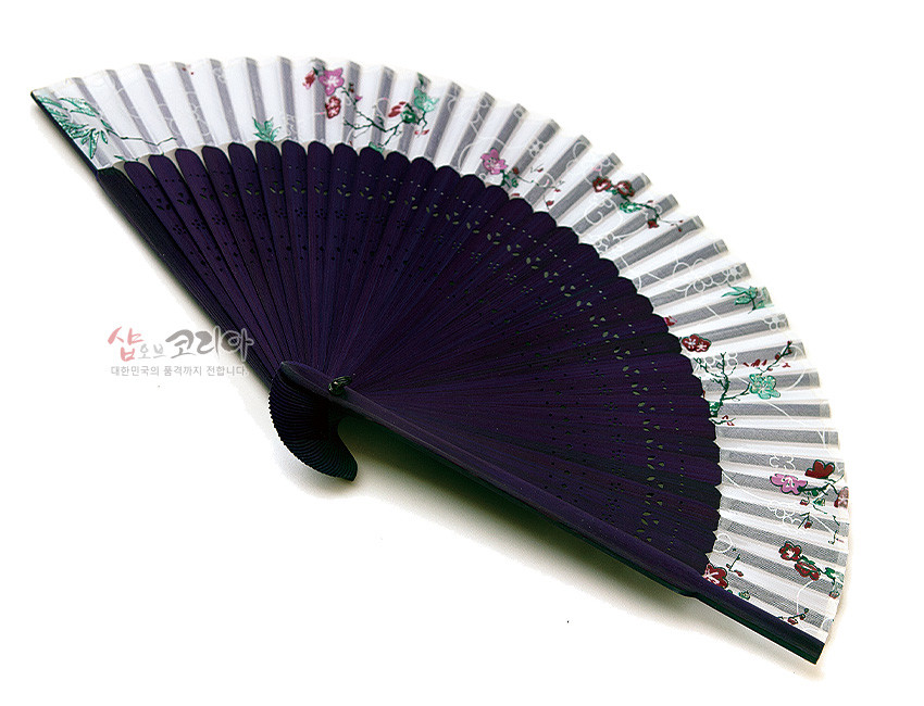 [텍스트: 샵오브코리아 대한민국의 품격까지 전합니다] 흰색 실크에 매화와 꽃문양이 채색되고 짙은 보라색 나뭇살에 섬세한 타공 장식을 더한 전통 수공 부채 모습