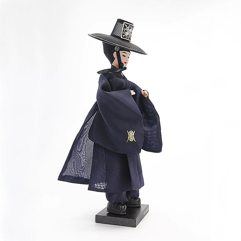 [텍스트: 없음] 짙은 남색 비단 저고리와 도포, 갓을 갖춘 저승사자 한복인형, 소매의 금색 한자 자수와 섬세한 직물 질감이 돋보이는 전통 공예품 형상