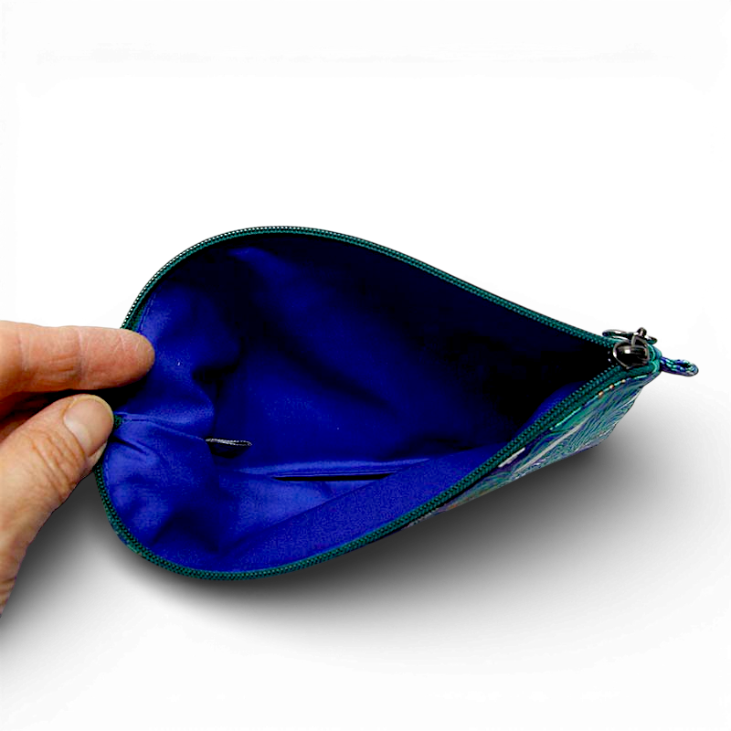 짙은 청색 안감과 초록색 지퍼가 대비되는 패브릭 파우치 내부 모습, 매끄러운 천 재질과 금속 지퍼 장식이 돋보이는 구조형 디자인